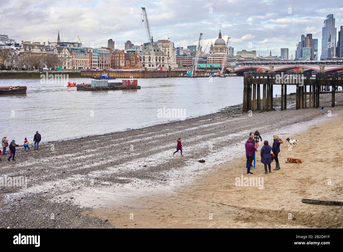 Le bord de mer à marée basse sur la Tamise près du quai de Gabriel sur Southbank avec des gens et des chiens sur la plage Banque D'Images