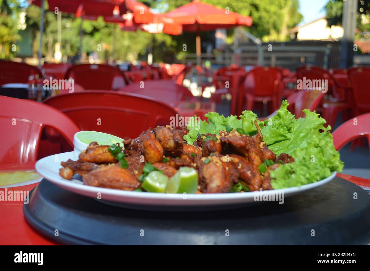 Aile de poulet frit avec ail et citron. Plat de restaurant brésilien. Banque D'Images