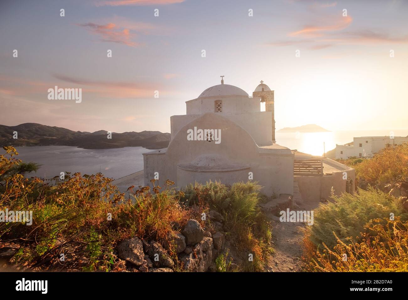 Coucher de soleil à Plaka, la ville principale de l'île de Milos sur la colline de Kastro. Vue de dessus en soirée magnifique, Grèce. Ancienne forteresse et ancienne église. L'eau paisible de Banque D'Images