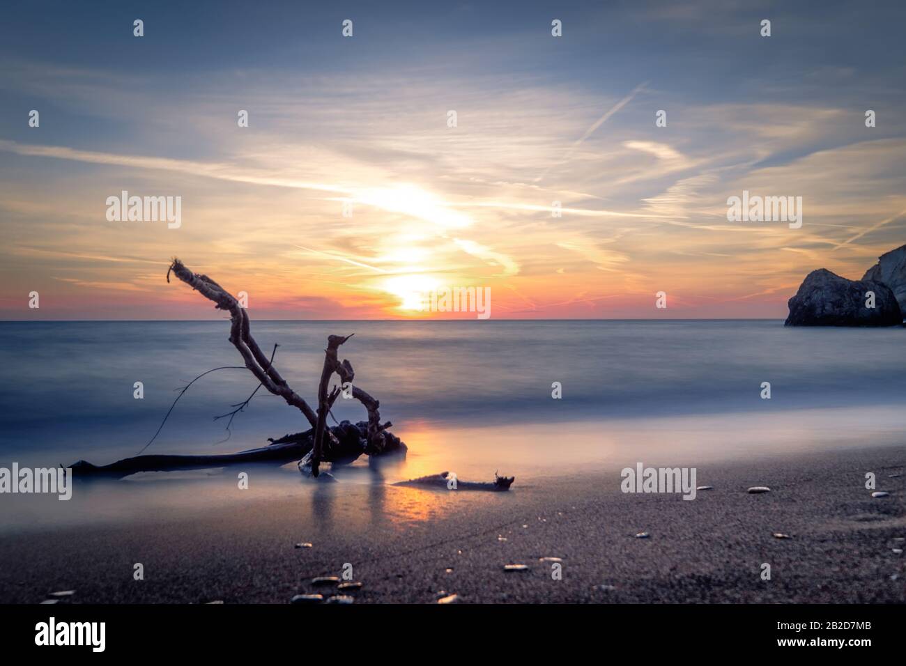 Magnifique coucher de soleil sur l'île de Milos. Sur la plage de sable et le doux surf de la mer Egée. De grandes roches de pierre dans l'eau. Paisible soirée paysage méditerranéen sur Banque D'Images