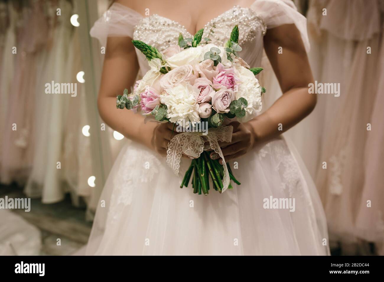 Bouquet tenant par Bode elle porte une robe de mariage blanche à la  boutique de mariage. Photo sans visage Photo Stock - Alamy