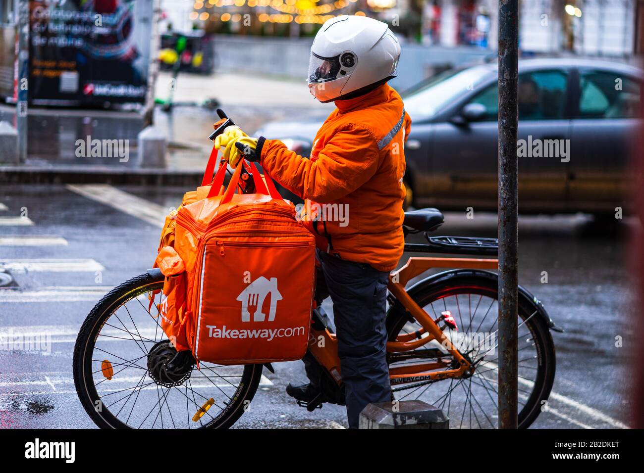 Jeune homme sur un vélo électrique avec le logo takeaway.com fournissant de la nourriture pendant une journée de pluie à Bucarest, Roumanie, 2020 Banque D'Images