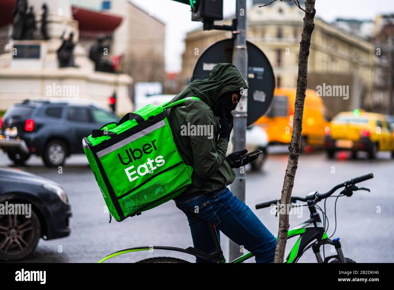 Jeune homme sur un vélo avec le logo Uber Eats fournissant de la nourriture pendant une journée de pluie à Bucarest, Roumanie, 2020 Banque D'Images