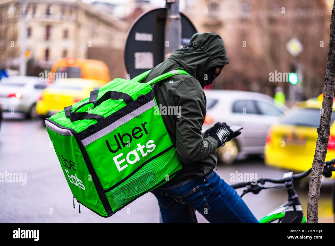 Jeune homme sur un vélo avec le logo Uber Eats fournissant de la nourriture  pendant une journée de pluie à Bucarest, Roumanie, 2020 Photo Stock - Alamy