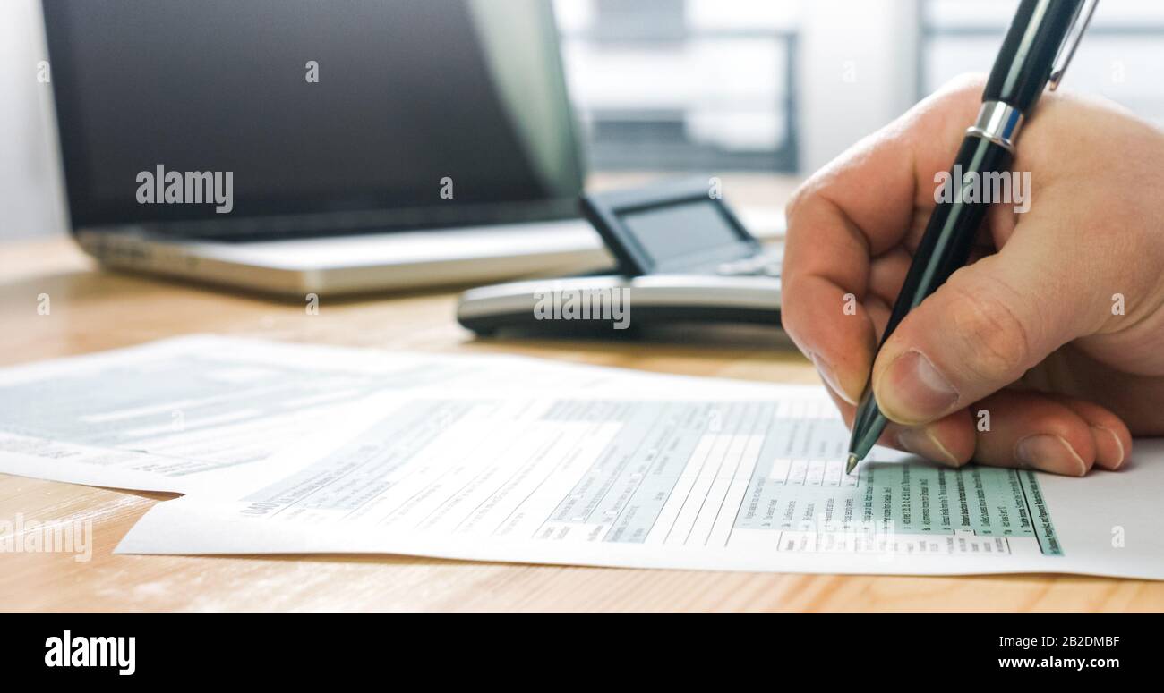 Gros plan du formulaire d'impôt américain 1040 et calcul et remplissage manuel du papier de rapport avec un ordinateur portable au bureau. Banque D'Images