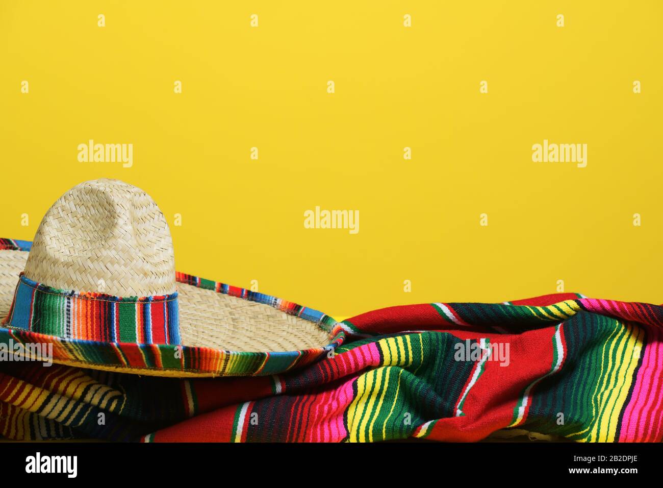Sombrero mexicain sur une couverture en serape colorée sur un fond jaune. Thème Cinco de Mayo Banque D'Images