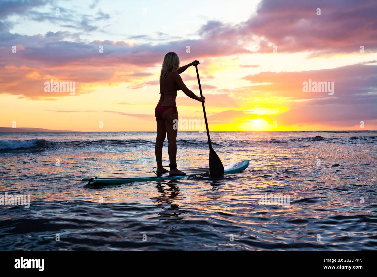 Une femme active paddle un paddle debout au coucher du soleil à Cove Park, Kihei, Maui, Hawaï. Banque D'Images