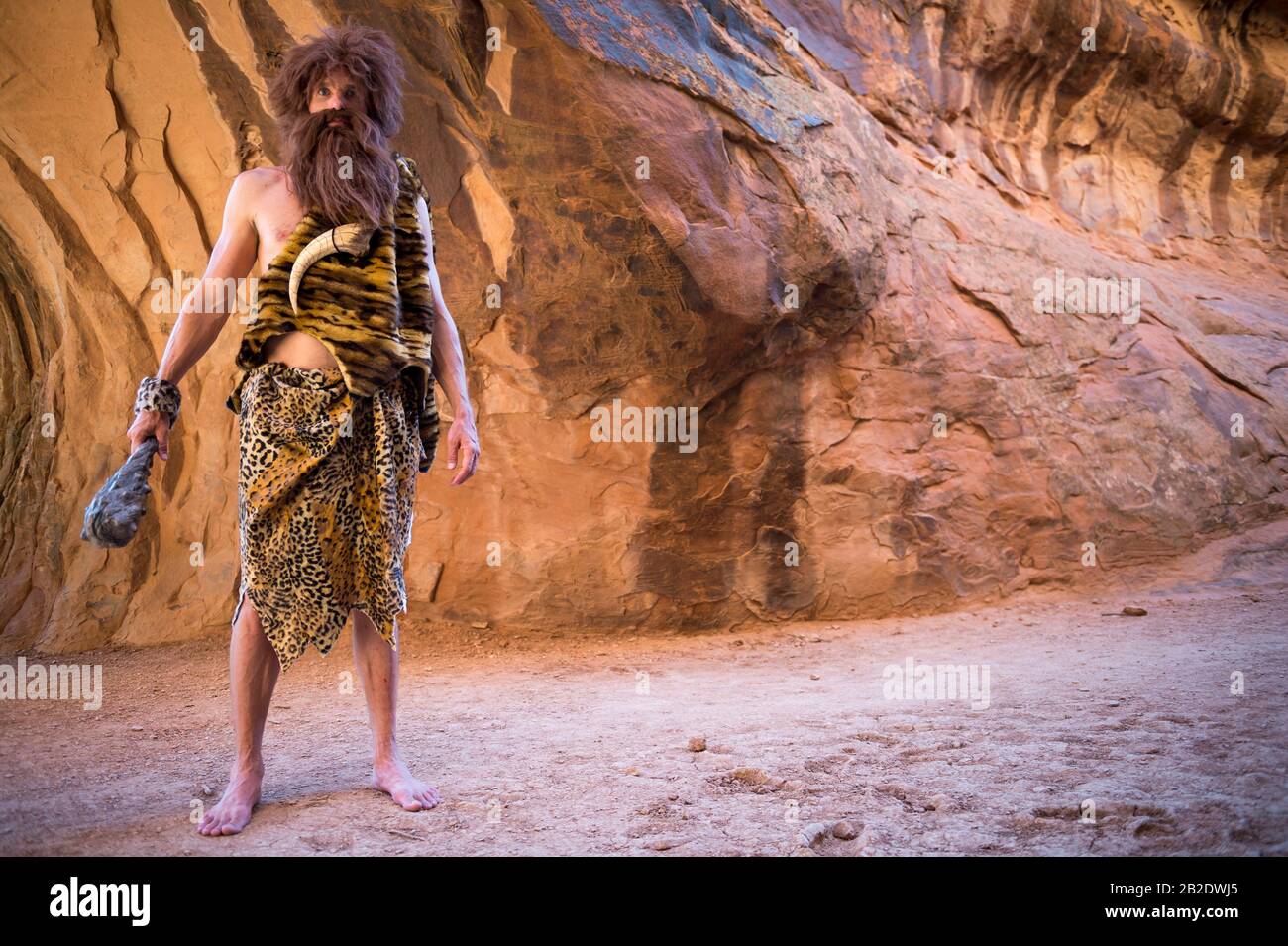 Caveman debout dehors tenant son club dans une grotte vide Banque D'Images