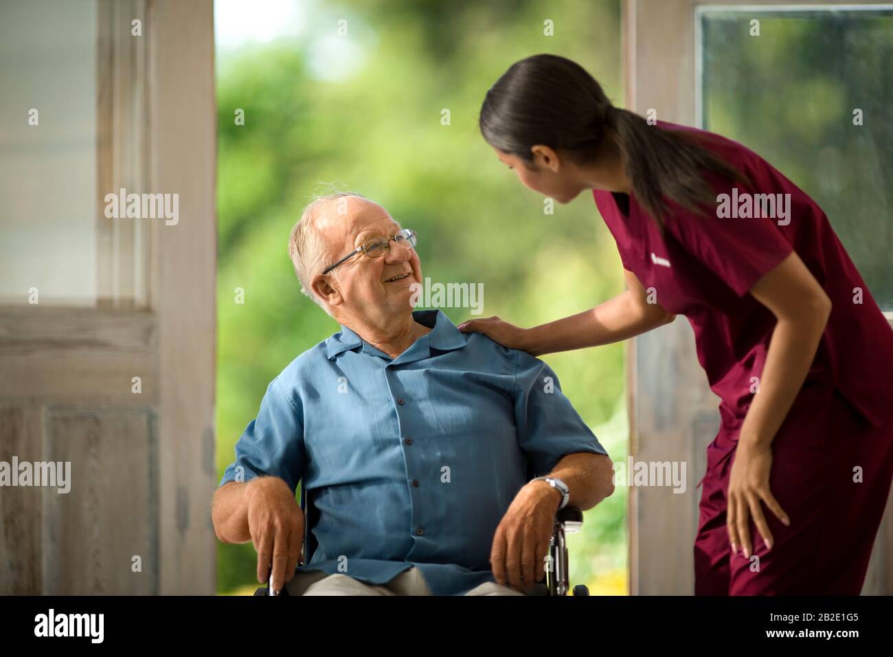 Homme senior souriant parlant à une jeune infirmière Banque D'Images