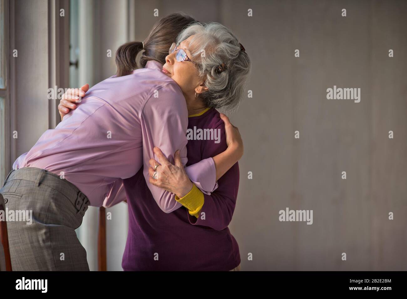 Le soignant adulte moyen et le patient âgé s'embrassent les uns les autres Banque D'Images