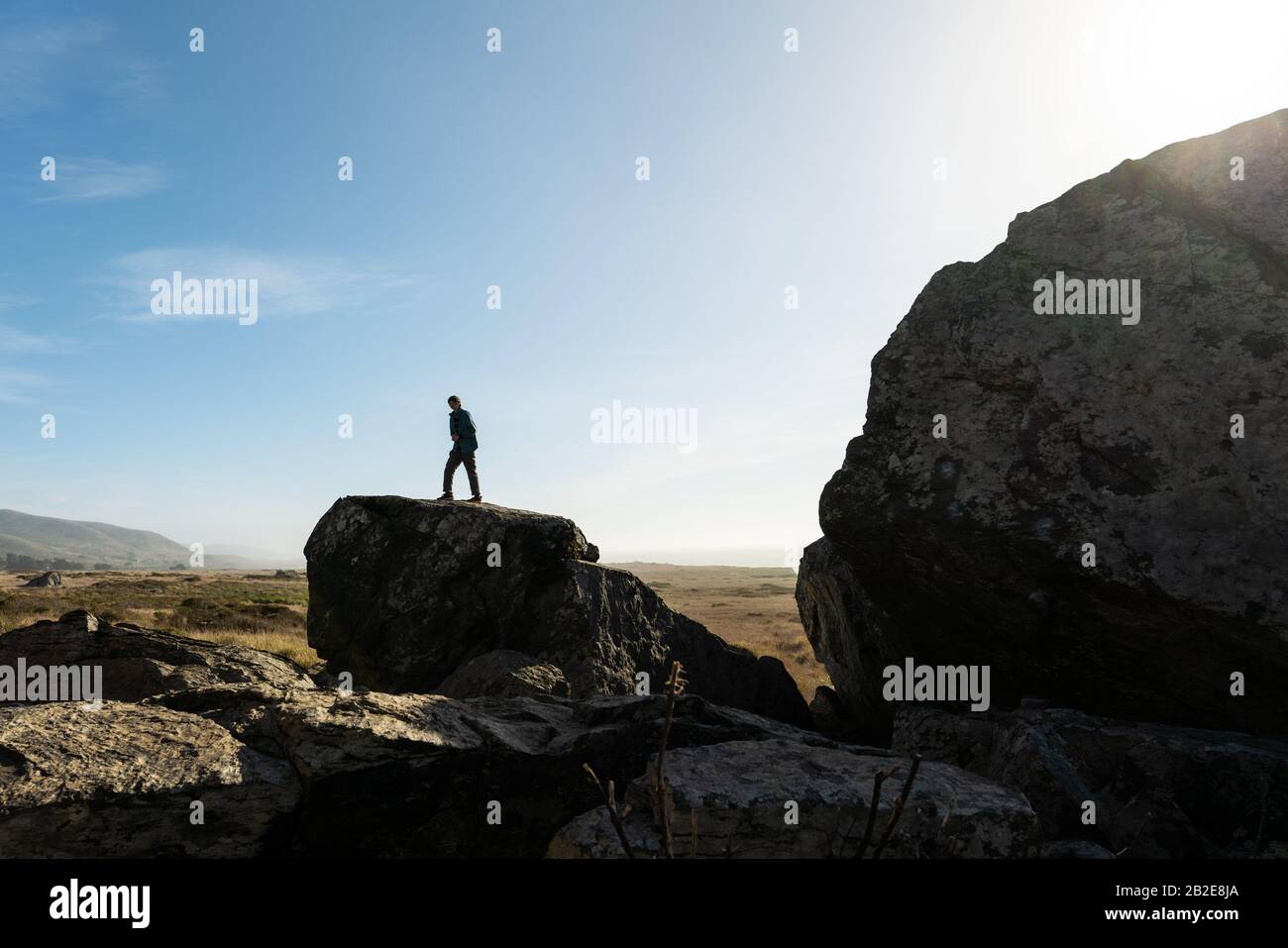 Personne seule silhouetée contre le ciel bleu debout sur le grand rocher Banque D'Images