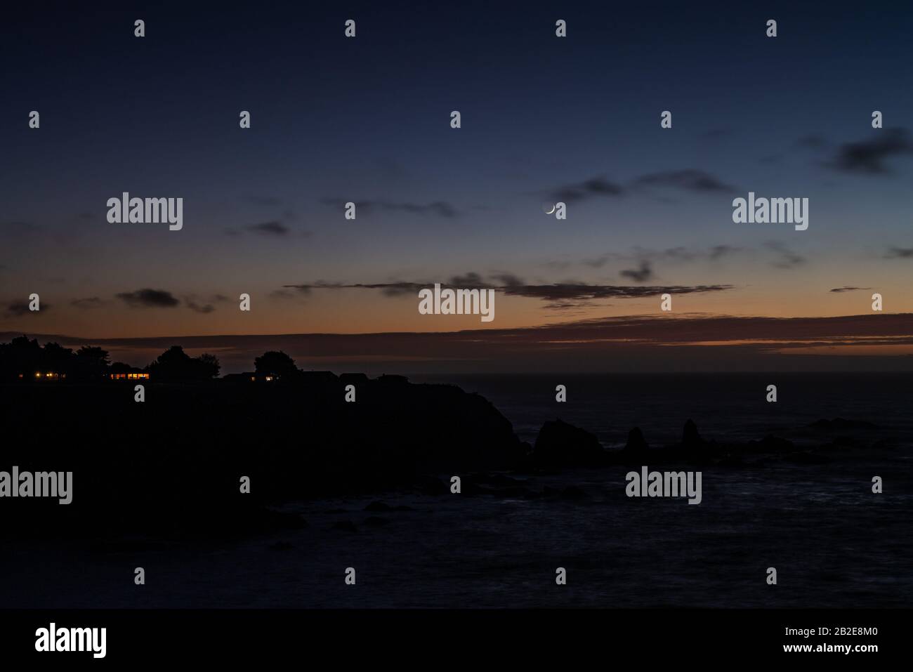Petit cottage sur la falaise côté océan sous le soleil et le croissant de lune Banque D'Images