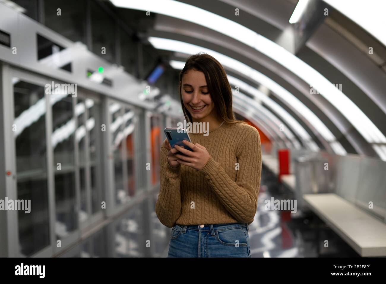 Jeune femme utilisant le téléphone cellulaire dans une station de métro moderne. Concept de technologie et de métro. Banque D'Images