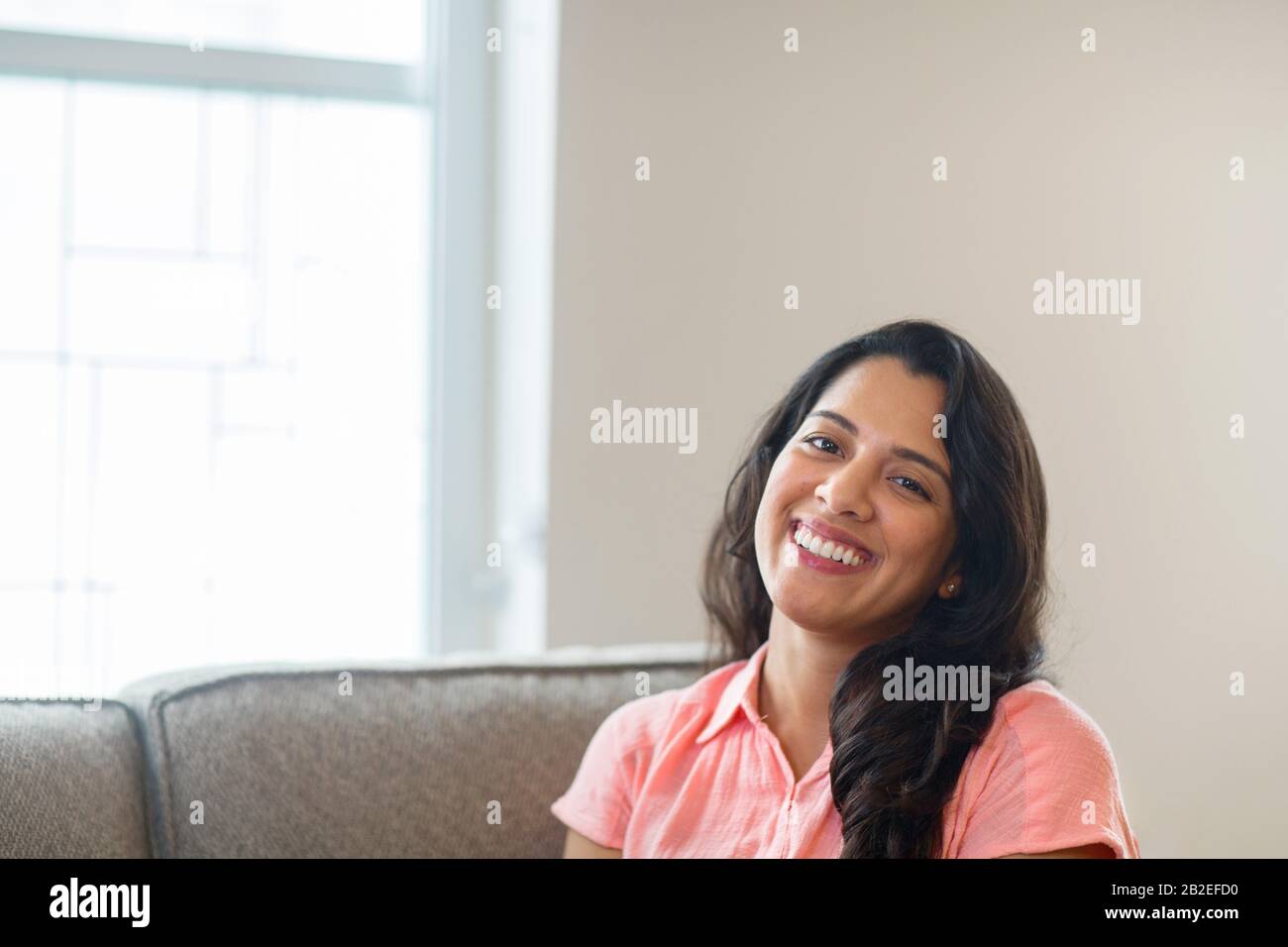 Jeune femme hispanique souriant assis sur un canapé. Banque D'Images