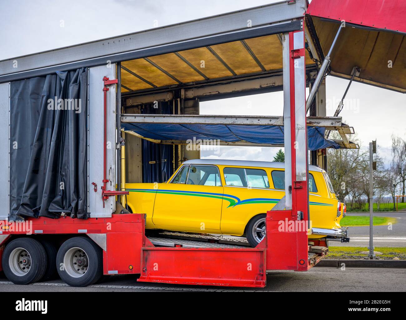 Remorque semi-remorque de transport de voiture rouge, ouverte et puissante, avec palan à l'intérieur et rideaux pour le transport de voiture de sécurité sur la route et non chargée Banque D'Images