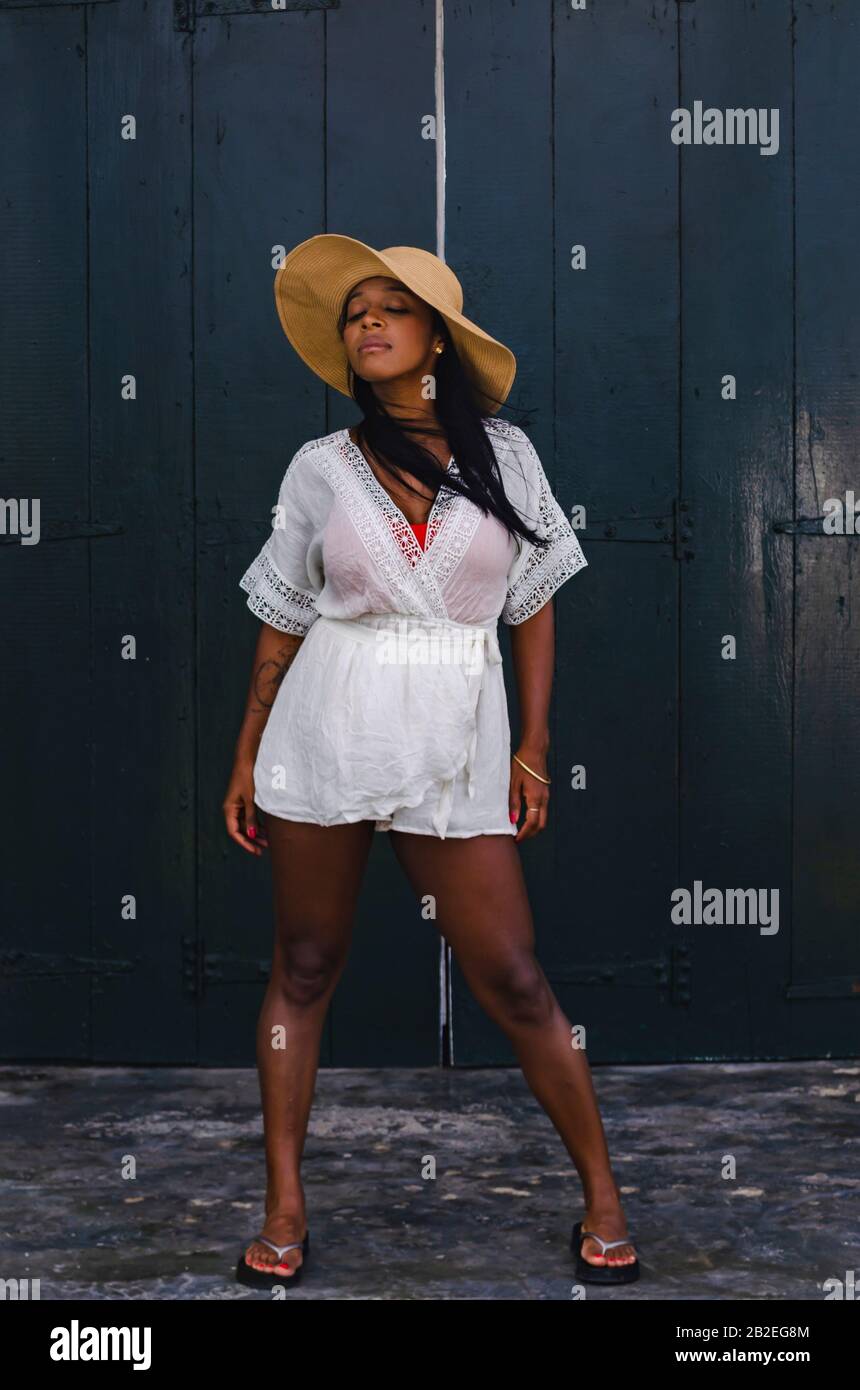 Femme noire de 25 à 30 ans, devant une porte d'église, vêtue de modèles blancs, de vêtements frais d'été et tropicaux. Banque D'Images