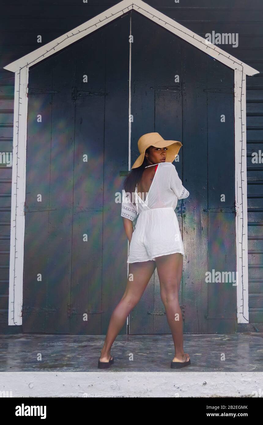 Femme noire de 25 à 30 ans, devant une porte d'église, vêtue de modèles blancs, de vêtements frais d'été et tropicaux. Banque D'Images