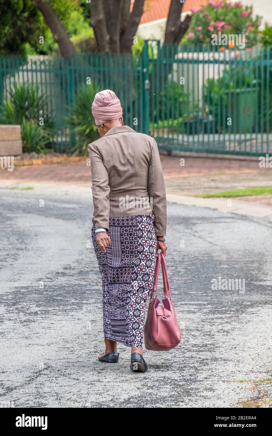 Alberton, Afrique du Sud - une femme africaine noire non identifiée bien habillée marche dans une rue résidentielle de la ville Banque D'Images