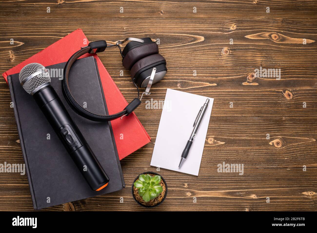 Microphone avec vue sur le dessus, casque, livre et note en papier sur une planche en bois marron. Apprendre à parler de concept Banque D'Images