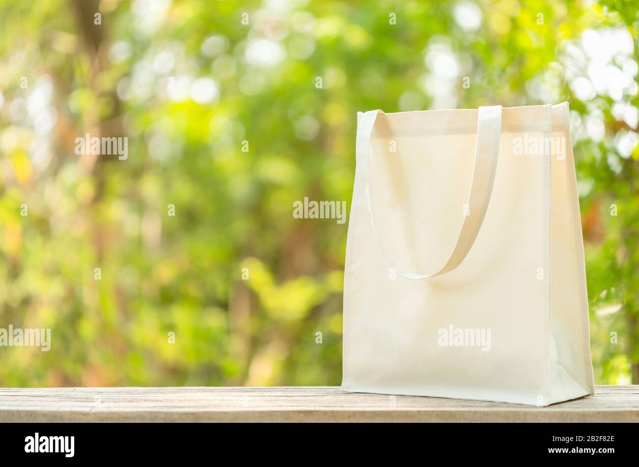 Sac blanc en coton mis sur table en bois avec espace pour le texte ou la publicité. Le sac en coton peut être utilisé pour faire des achats pour remplacer le sac en plastique sur le sac vert nature Banque D'Images