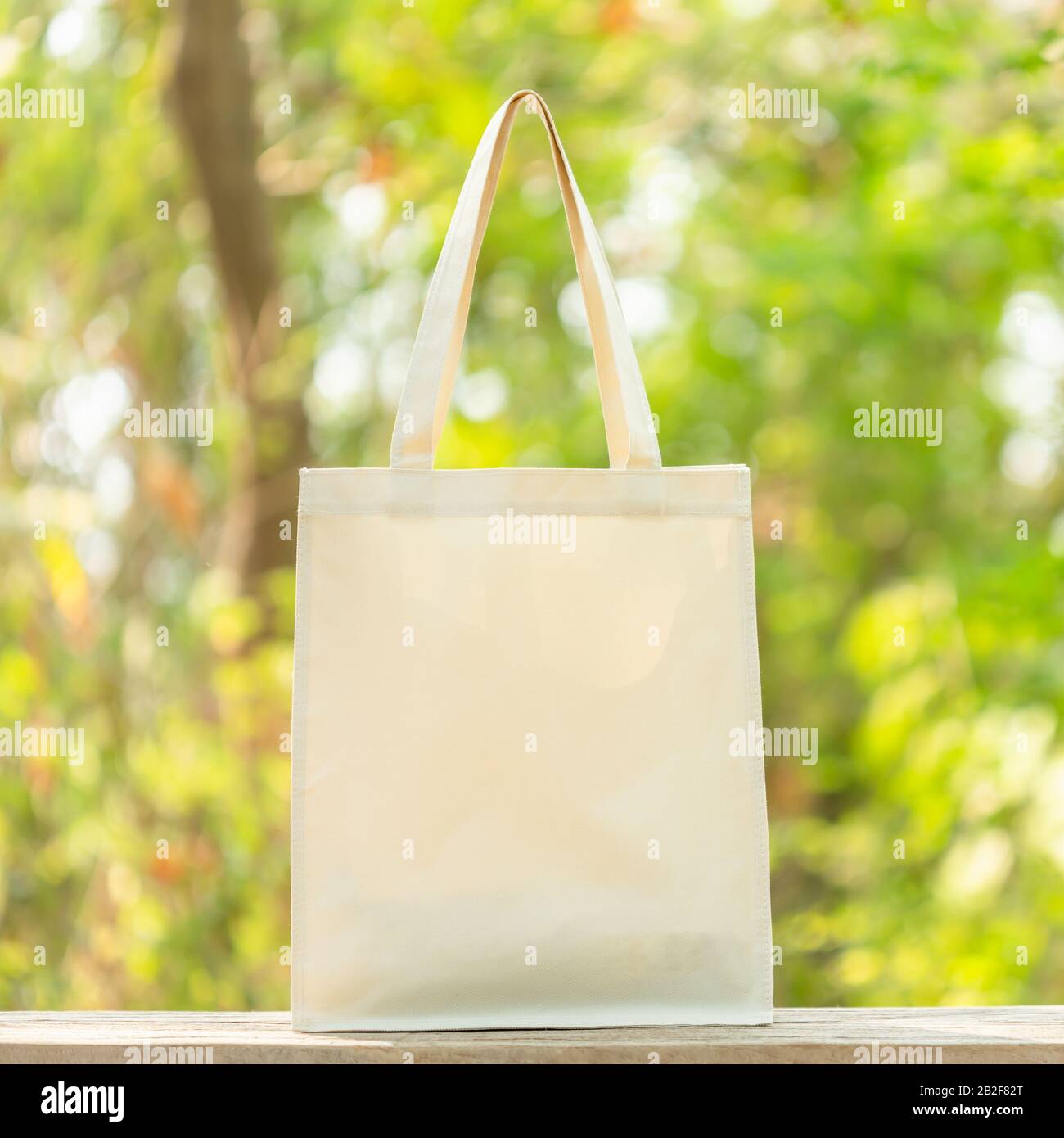 Sac blanc en coton mis sur table en bois avec espace pour le texte ou la publicité. Le sac en coton peut être utilisé pour faire des achats pour remplacer le sac en plastique sur le sac vert nature Banque D'Images