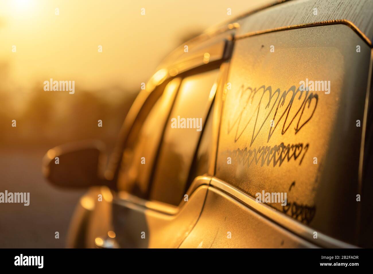 Petite fille asiatique écrivant ou dessinant le symbole du coeur sur le miroir humide de son père SUV voiture le matin pour le concept d'amour Banque D'Images