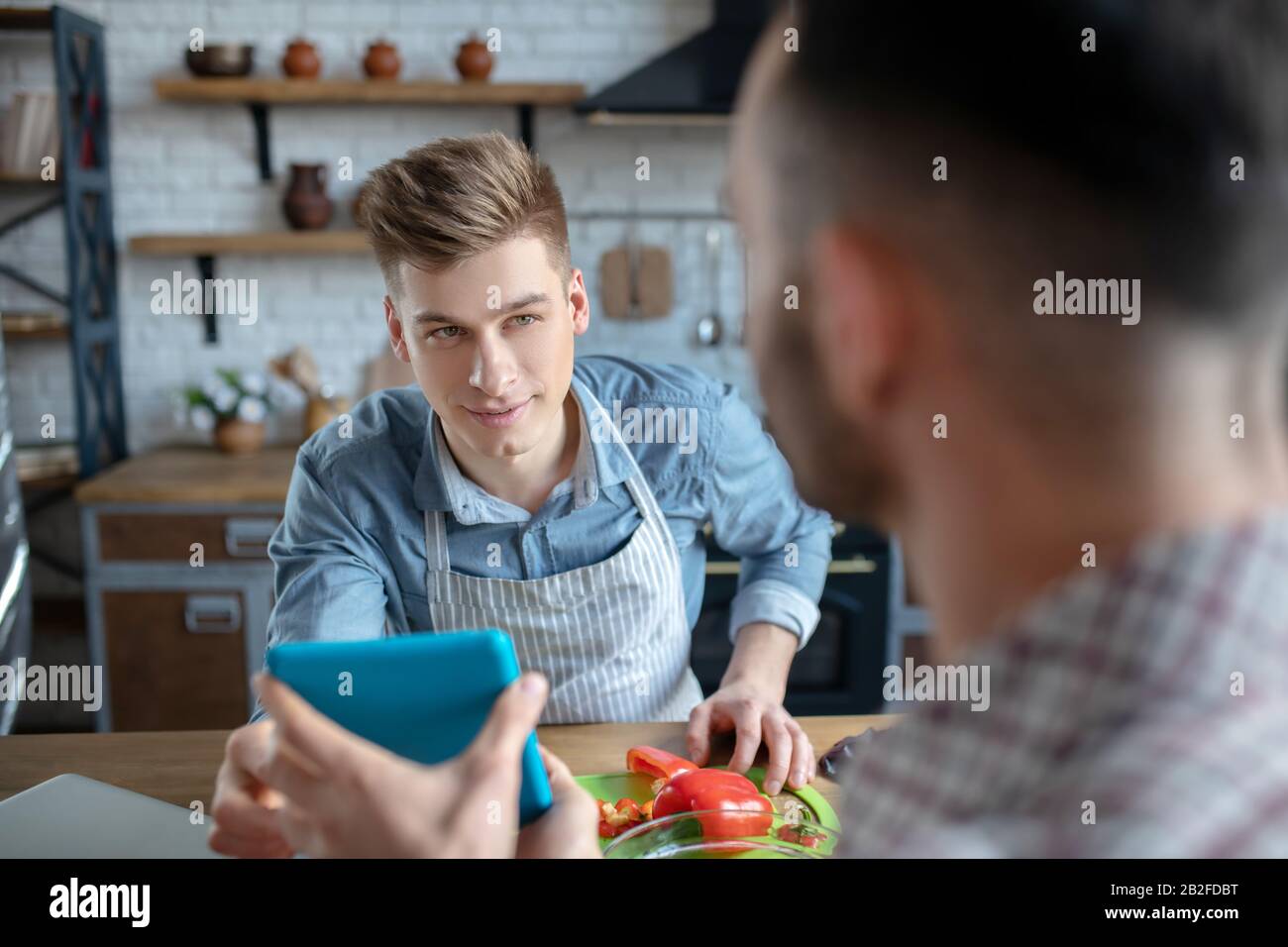 Deux hommes dans la cuisine à la table parler. Banque D'Images