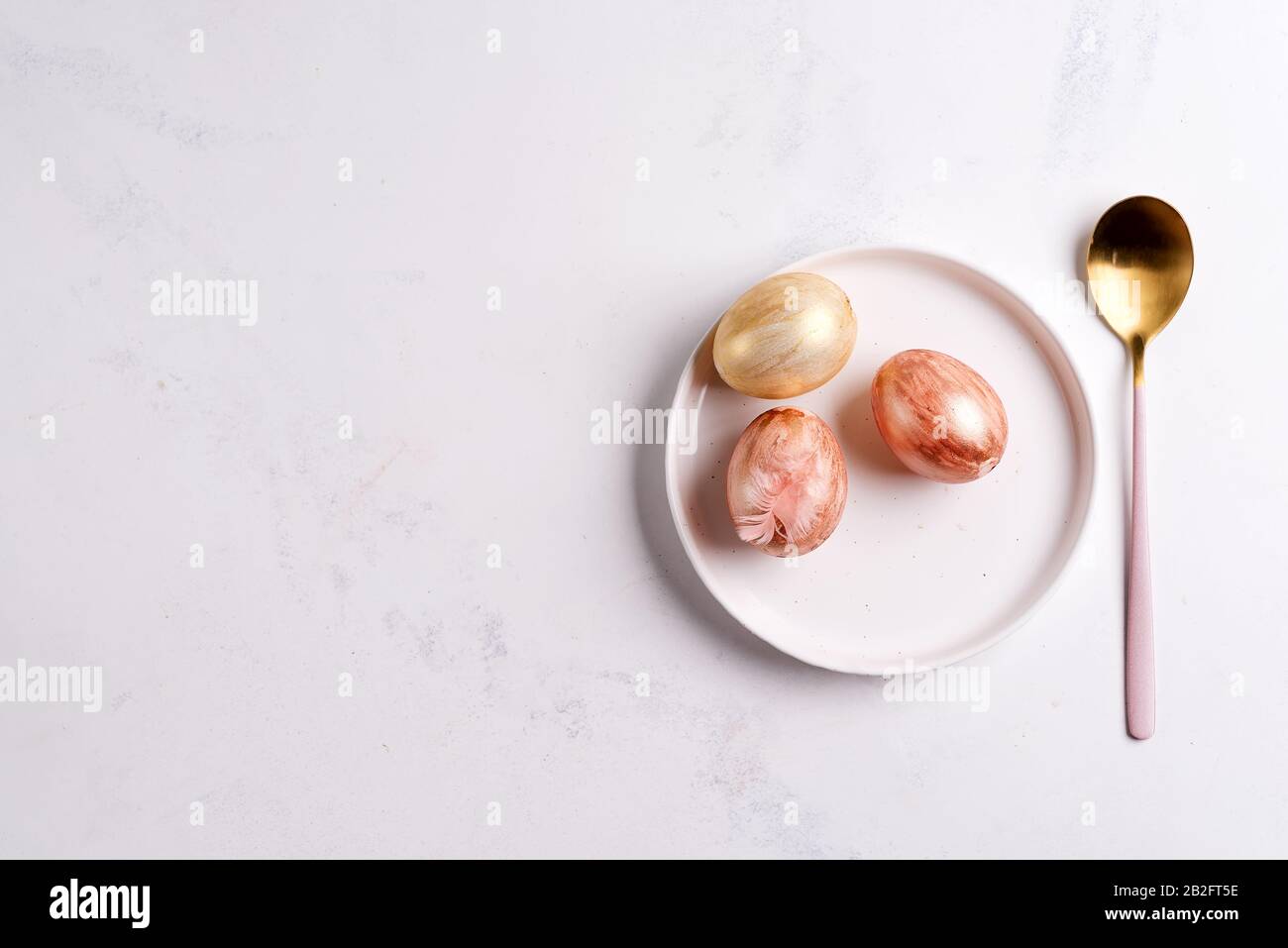 Table de Pâques située au-dessus. Élégante assiette vide, cutleryet œufs dorés sur pierre Banque D'Images