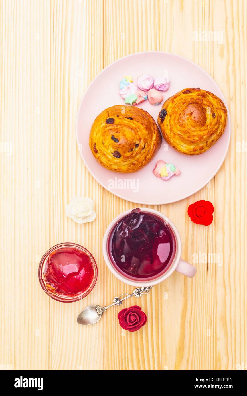 Thé Karkade à partir de pétales d'hibiscus (rose soudanaise). Petit déjeuner romantique et doux. Petits pains, meringues, gelée de fraises. Sur un fond en bois, haut vi Banque D'Images