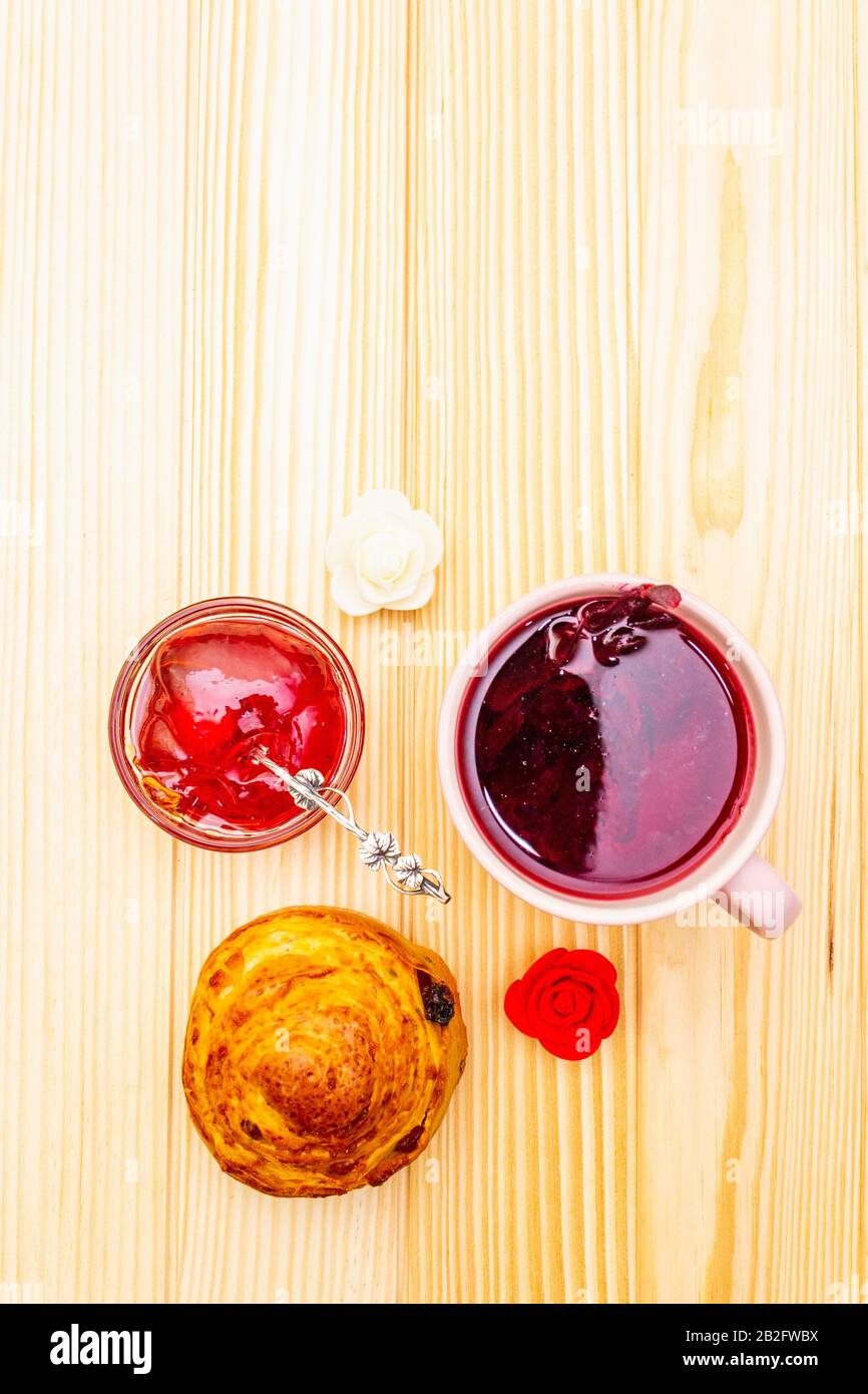 Thé Karkade à partir de pétales d'hibiscus (rose soudanaise). Petit déjeuner romantique et doux. Petits pains, meringues, gelée de fraises. Sur un fond en bois, haut vi Banque D'Images
