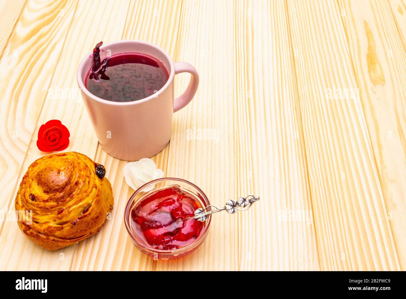 Thé Karkade à partir de pétales d'hibiscus (rose soudanaise). Petit déjeuner romantique et doux. Petits pains, meringues, gelée de fraises. Sur un fond en bois, copier s Banque D'Images