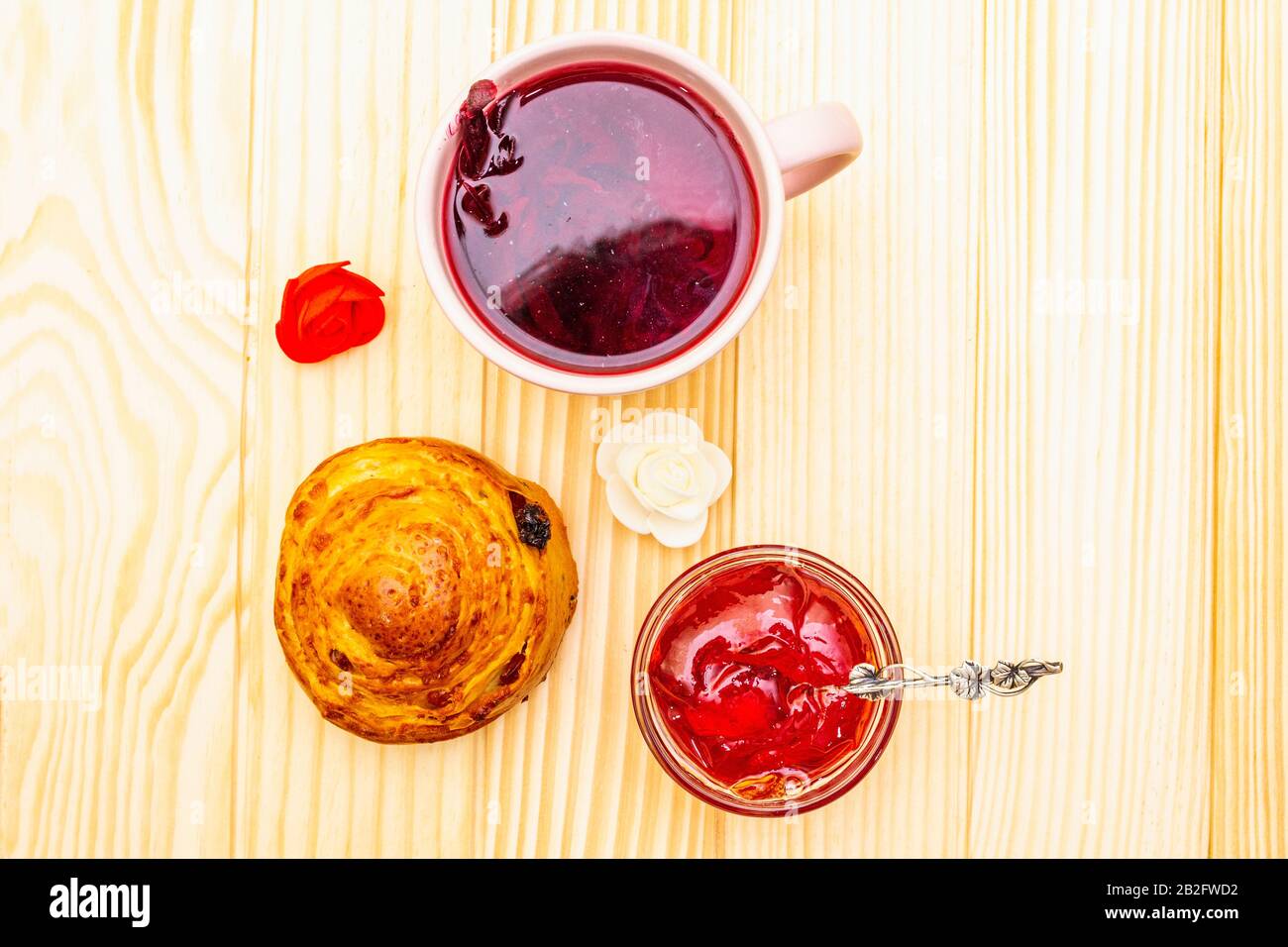 Thé Karkade à partir de pétales d'hibiscus (rose soudanaise). Petit déjeuner romantique et doux. Petits pains, meringues, gelée de fraises. Sur un fond en bois, haut vi Banque D'Images