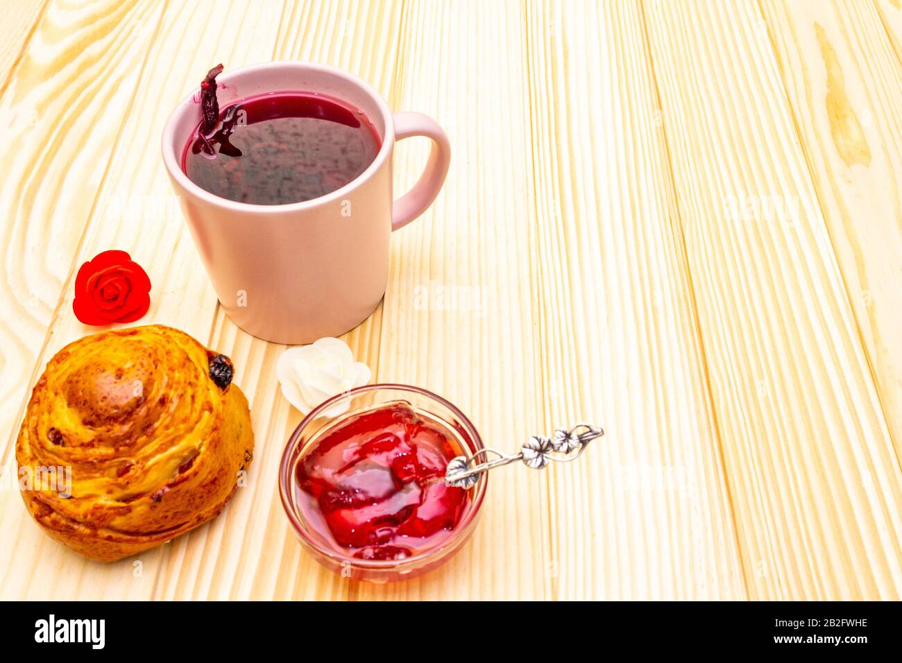 Thé Karkade à partir de pétales d'hibiscus (rose soudanaise). Petit déjeuner romantique et doux. Petits pains, meringues, gelée de fraises. Sur un fond en bois, copier s Banque D'Images