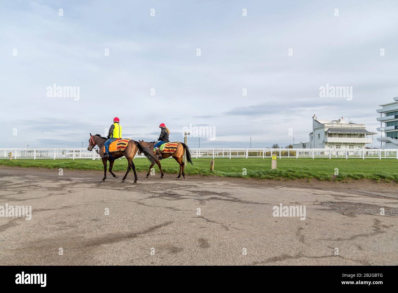Un jockey hommes et femmes chevaux d'exercice à l'hippodrome d'Epsom Downs. Le Princes Stand peut être vu à droite de la photo. Banque D'Images