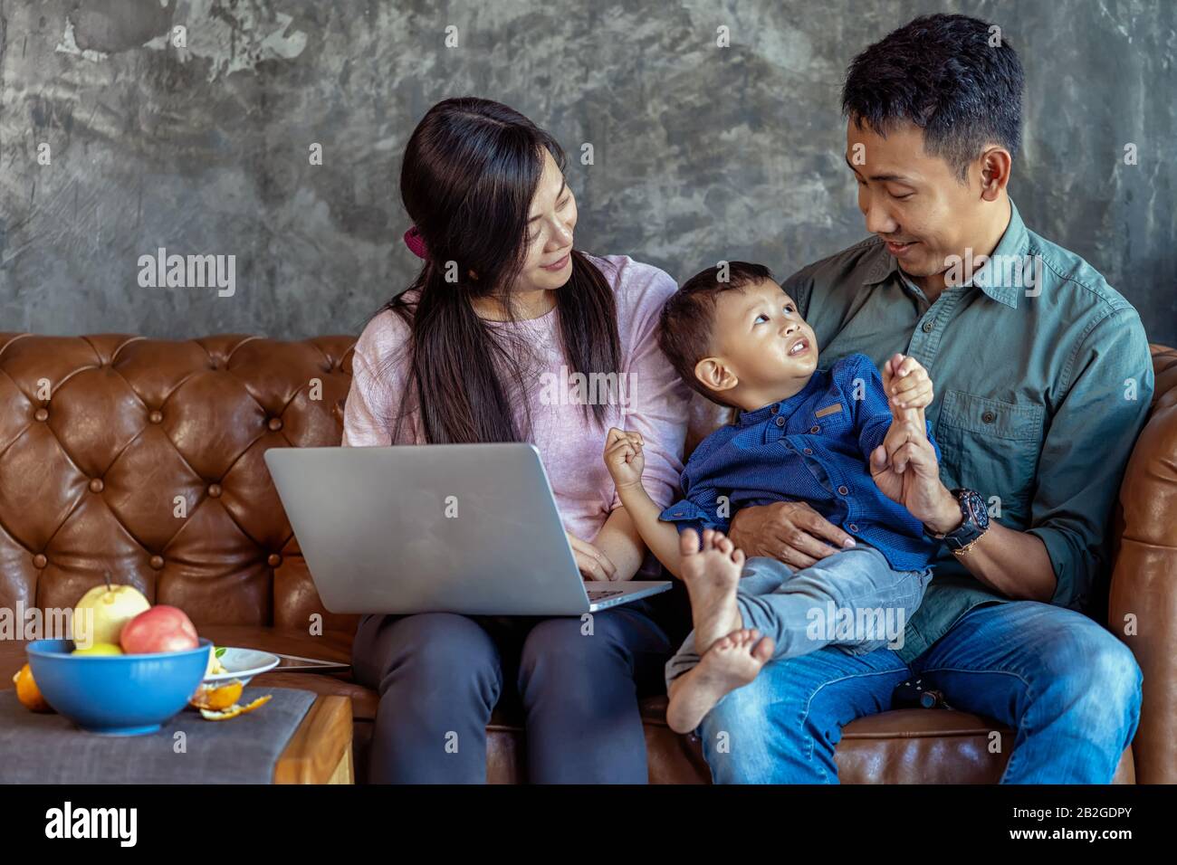 La famille asiatique avec son fils est à la recherche de la bande dessinée par ordinateur portable de technologie et de jouer ensemble lors de la vie dans la maison de loft pour l'auto-apprentissage ou l'école à la maison, Fa Banque D'Images