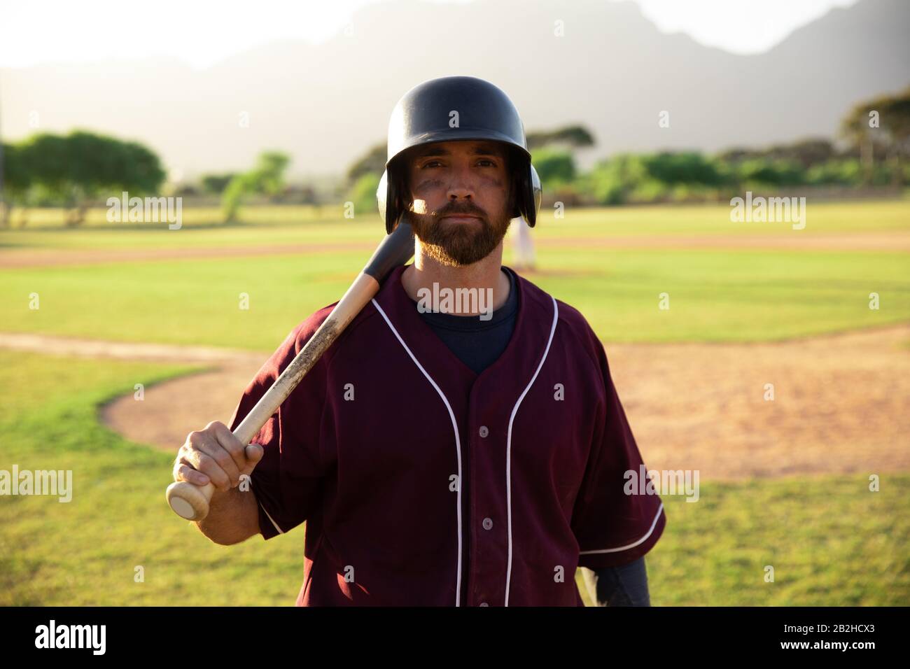 Joueur de base-ball regardant la caméra tenant une batte de base-ball et un casque Banque D'Images