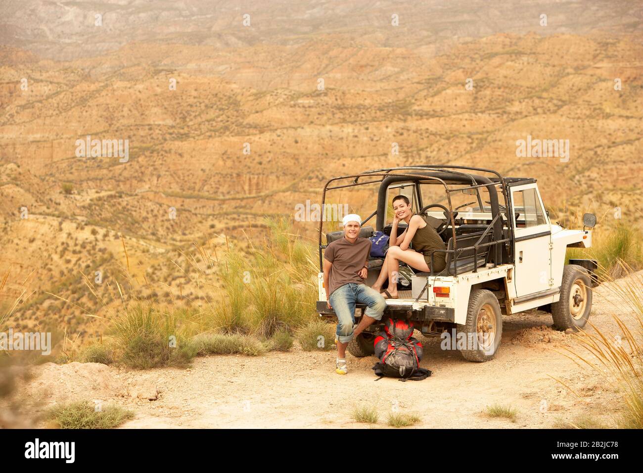 Couple assis à l'arrière de la voiture à quatre roues motrices sur le bord de la falaise dans le désert Banque D'Images