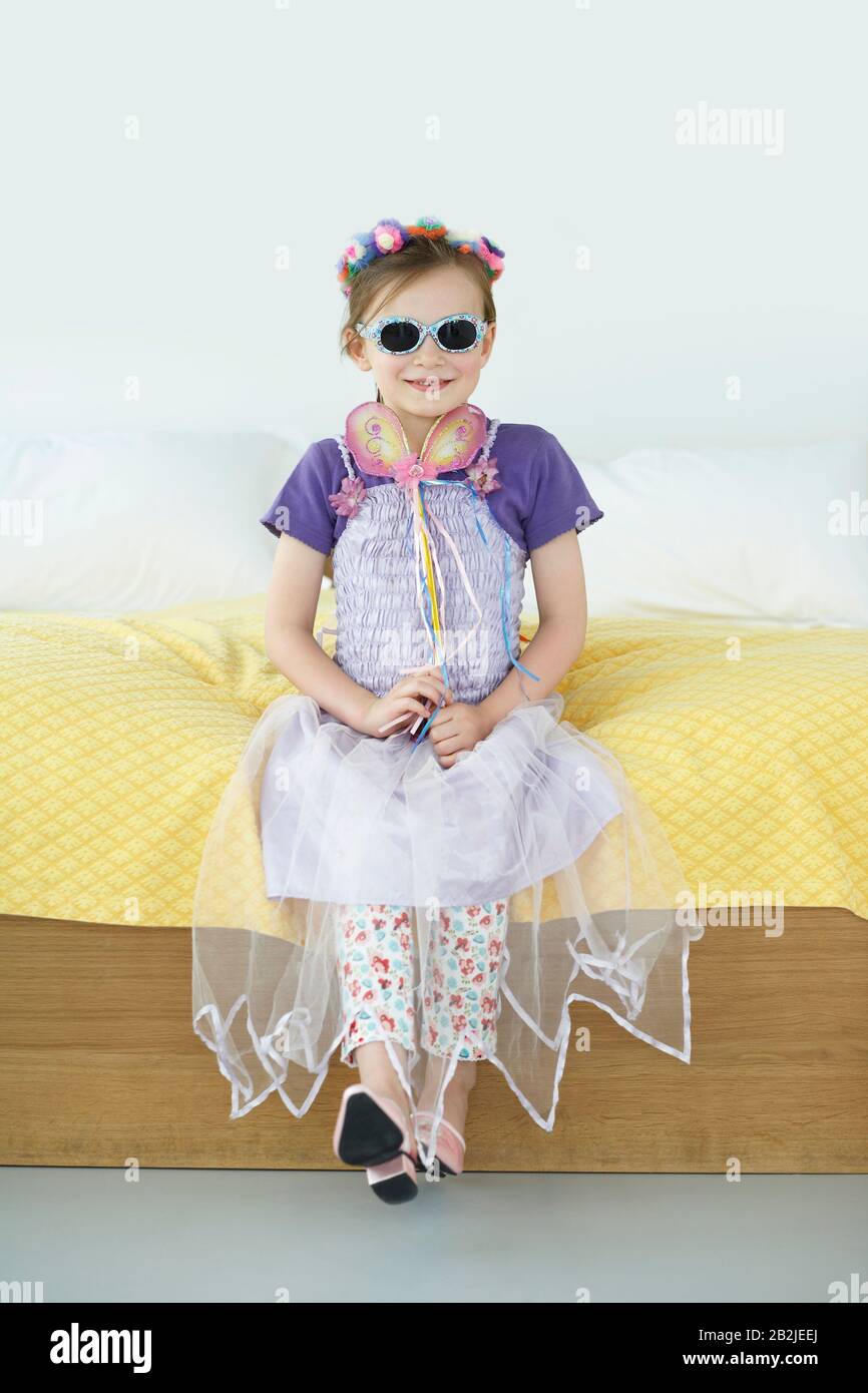 Fille (5-6) portant costume assis sur le portrait de lit Banque D'Images