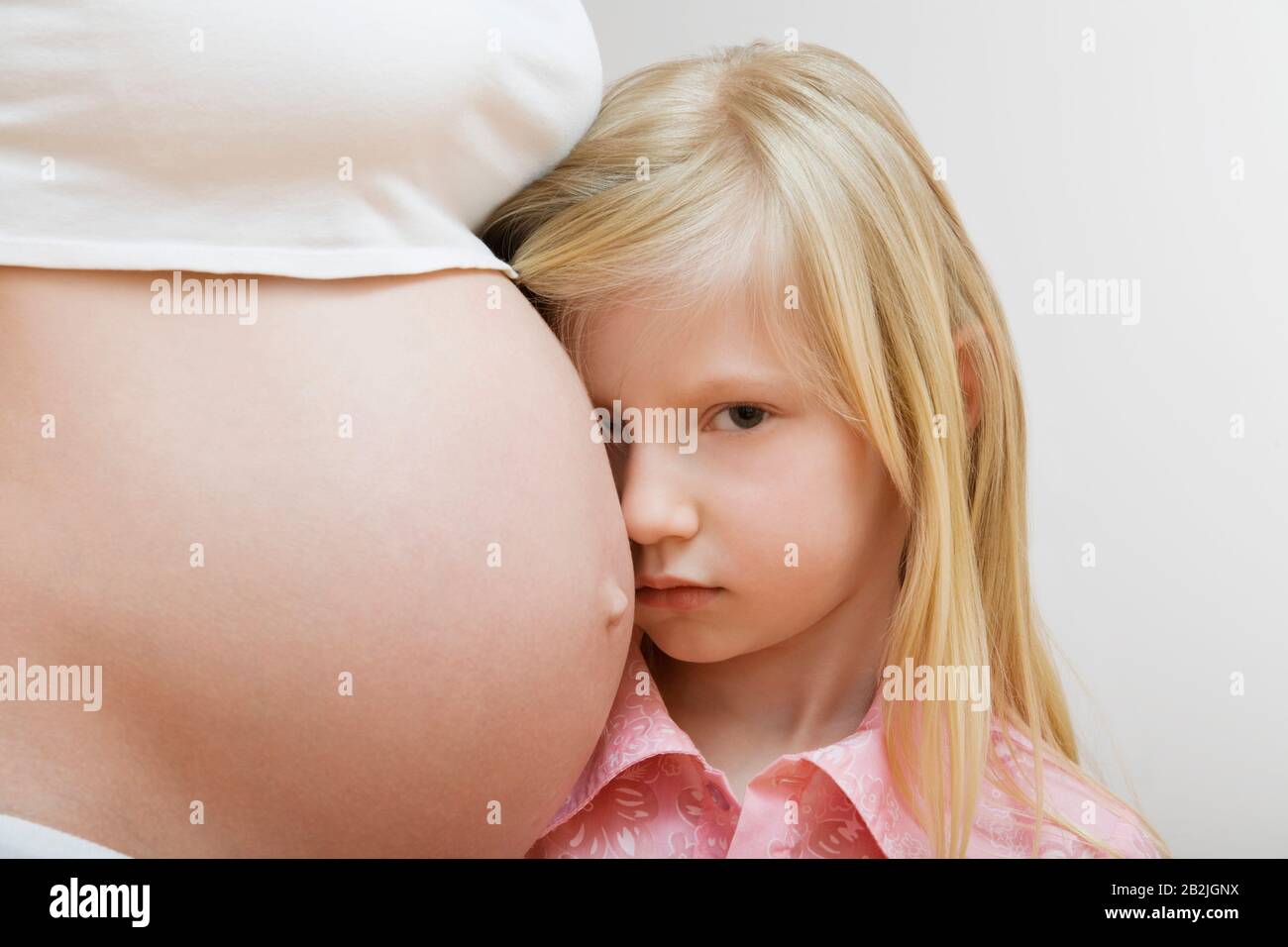 Portrait de fille (7-9) penchant sur le ventre de la mère enceinte Banque D'Images