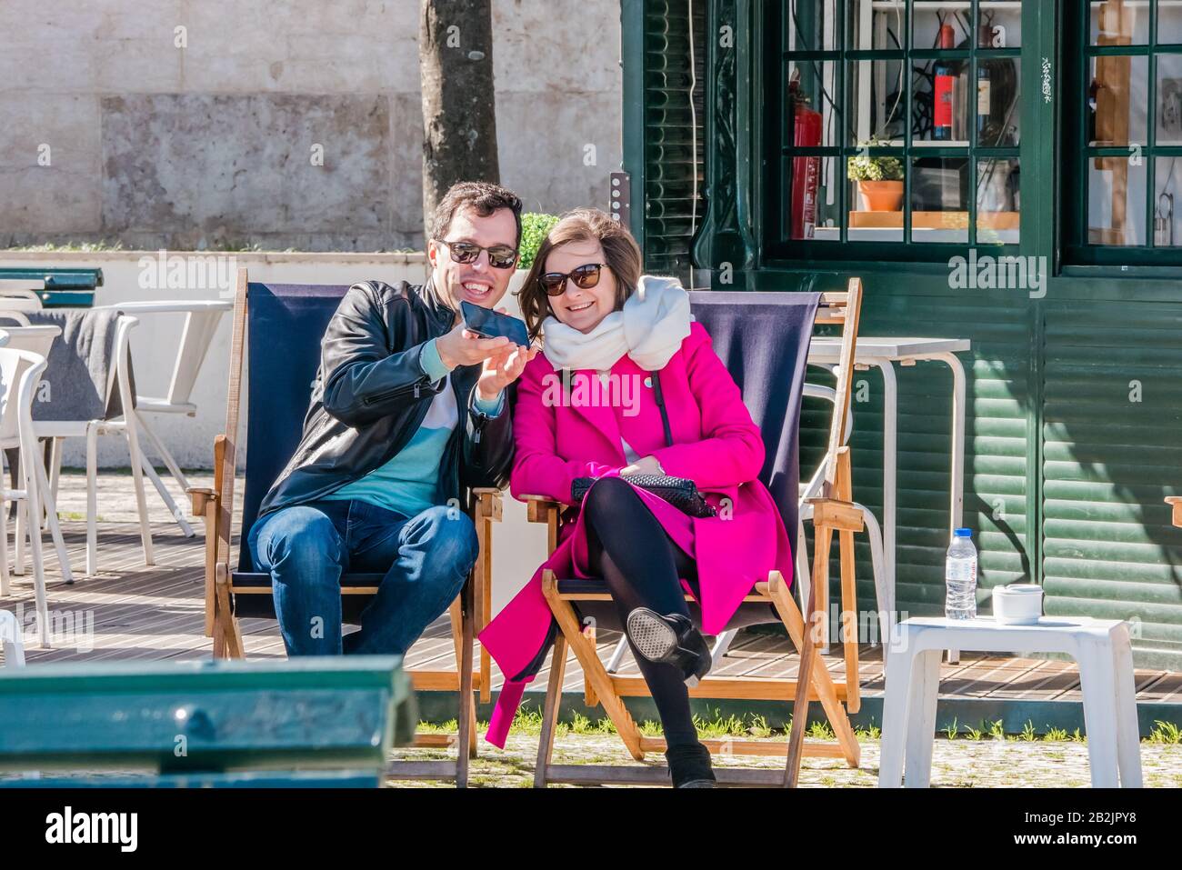 Les touristes masculins et féminins assis sur des chaises longues essayant de prendre un selfie pendant la saison d'hiver à Lisbonne Portugal Banque D'Images