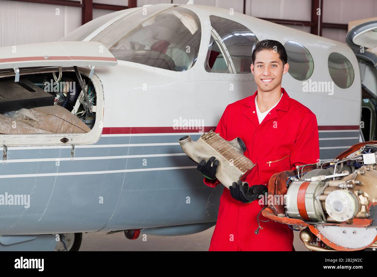 Portrait d'un mécanicien d'aviation masculin avec une partie de la machine devant l'avion Banque D'Images
