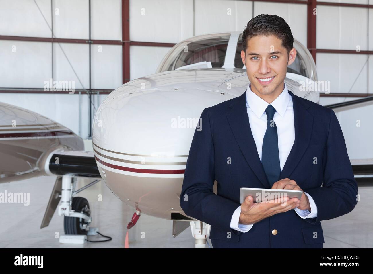 Portrait de beau jeune pilote utilisant un Tablet PC devant l'avion Banque D'Images