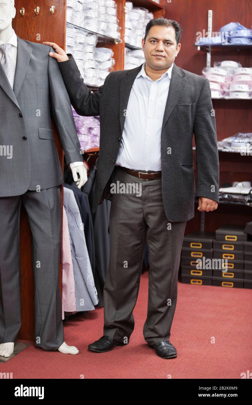 Portrait d'homme d'affaires debout par mannequin vêtu d'un costume dans un magasin de vêtements pour hommes Banque D'Images