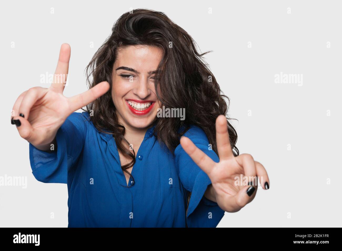 Une jeune femme heureuse signe de victoire gestuelle sur fond gris Banque D'Images