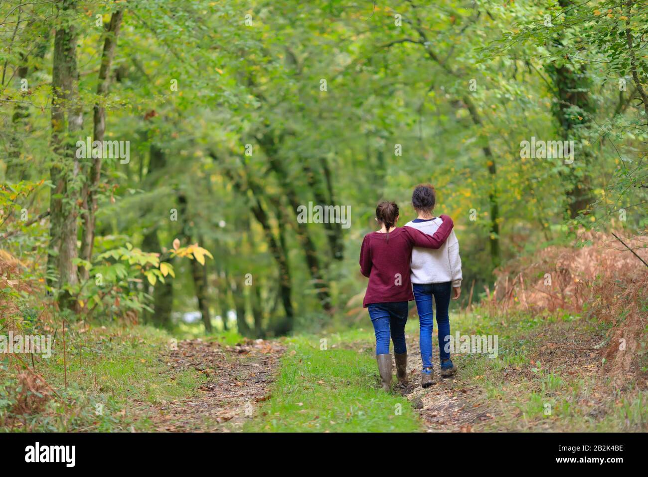 Deux adolescents non identifiés embrassant et marchant dans une forêt tempérée. Banque D'Images
