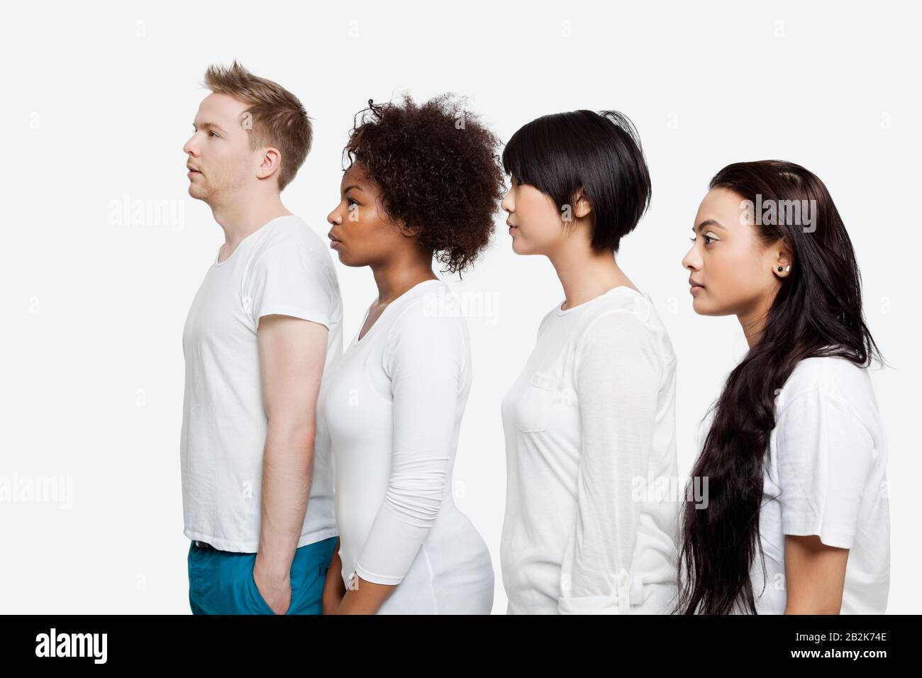Vue latérale de jeunes amis multiethniques dans des casuaux se tenant en ligne sur fond blanc Banque D'Images