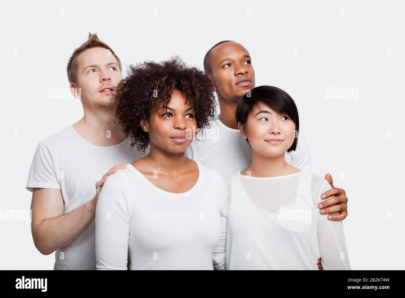 Jeunes amis multiethniques dans des t-shirts blancs regardant loin sur fond blanc Banque D'Images
