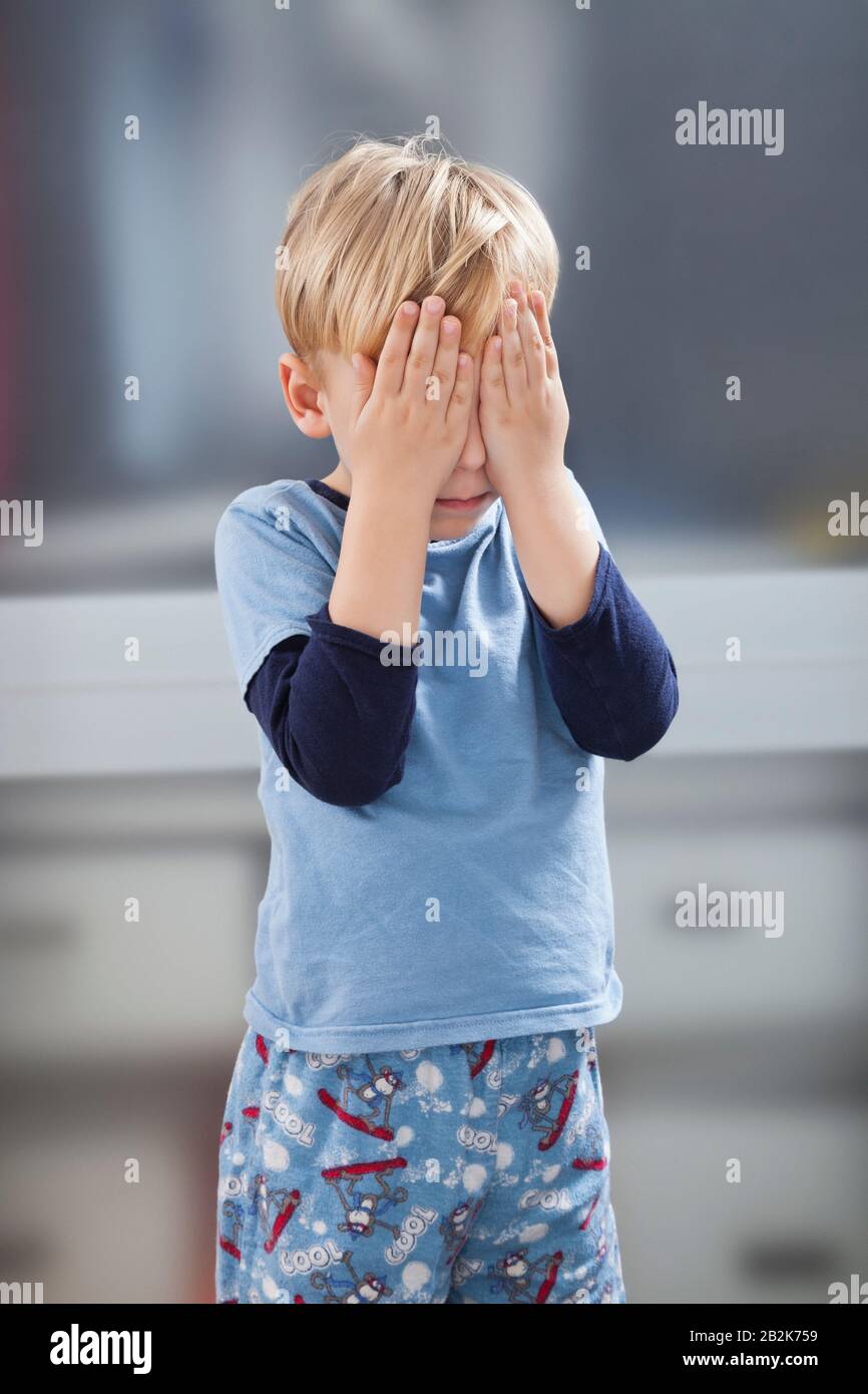 Un petit garçon effrayé en casual avec les mains sur les yeux Banque D'Images