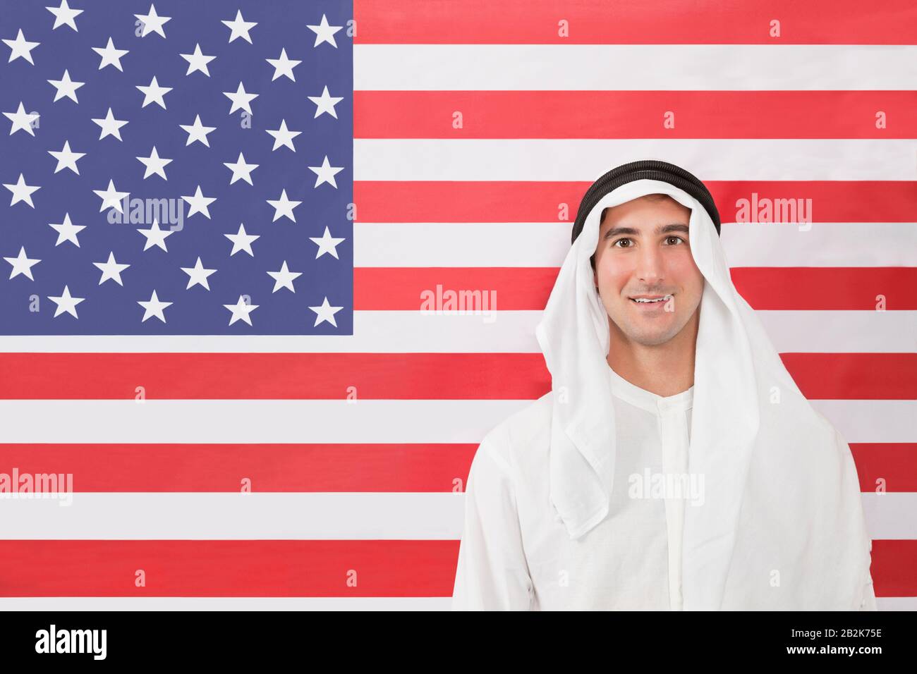 Portrait d'un homme arabe dans des vêtements traditionnels regardant contre le drapeau américain Banque D'Images