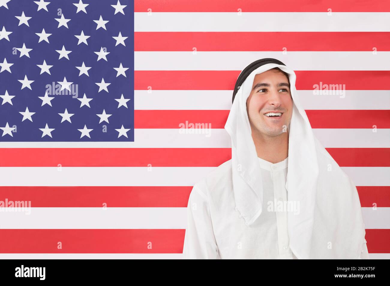Un homme arabe dans des vêtements traditionnels regardant contre le drapeau américain Banque D'Images